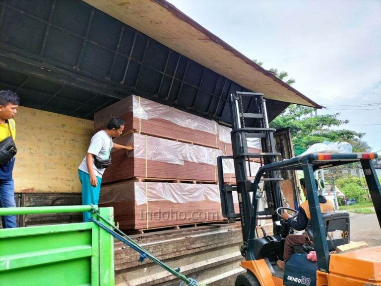 Proses bongkar muat triplek phenolic film face menggunakan forklift dari truk pengiriman di gudang distributor plywood.